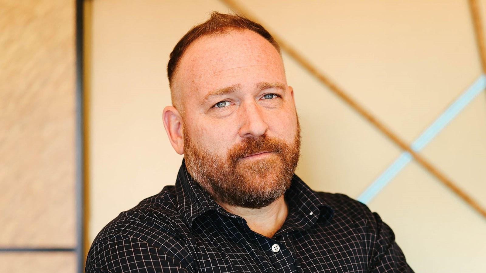 A shoulder-length photo of Ryan Little wearing a dark shirt standing in front of a light-colored background.