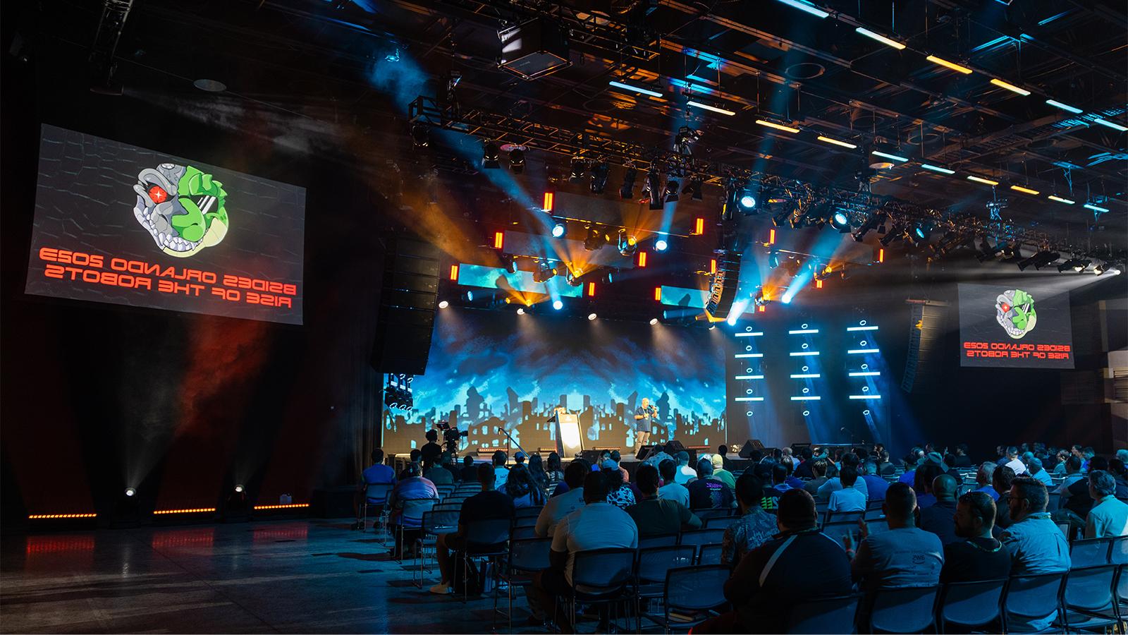 Attendees sit in the 满帆 Live venue. Screens with a lizard robot logo and the words BSides奥兰多 2023: Rise of the Robots are on either side of the stage.