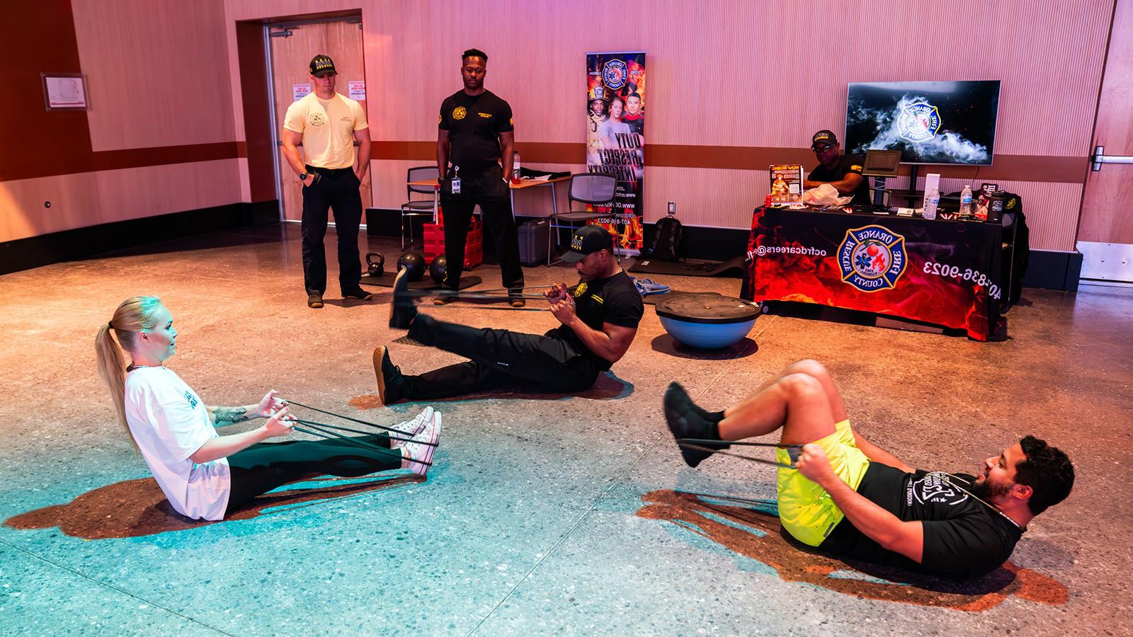 Two staff members take part in a bootcamp style workout instructed by a member of the Orange County Fire Rescue.