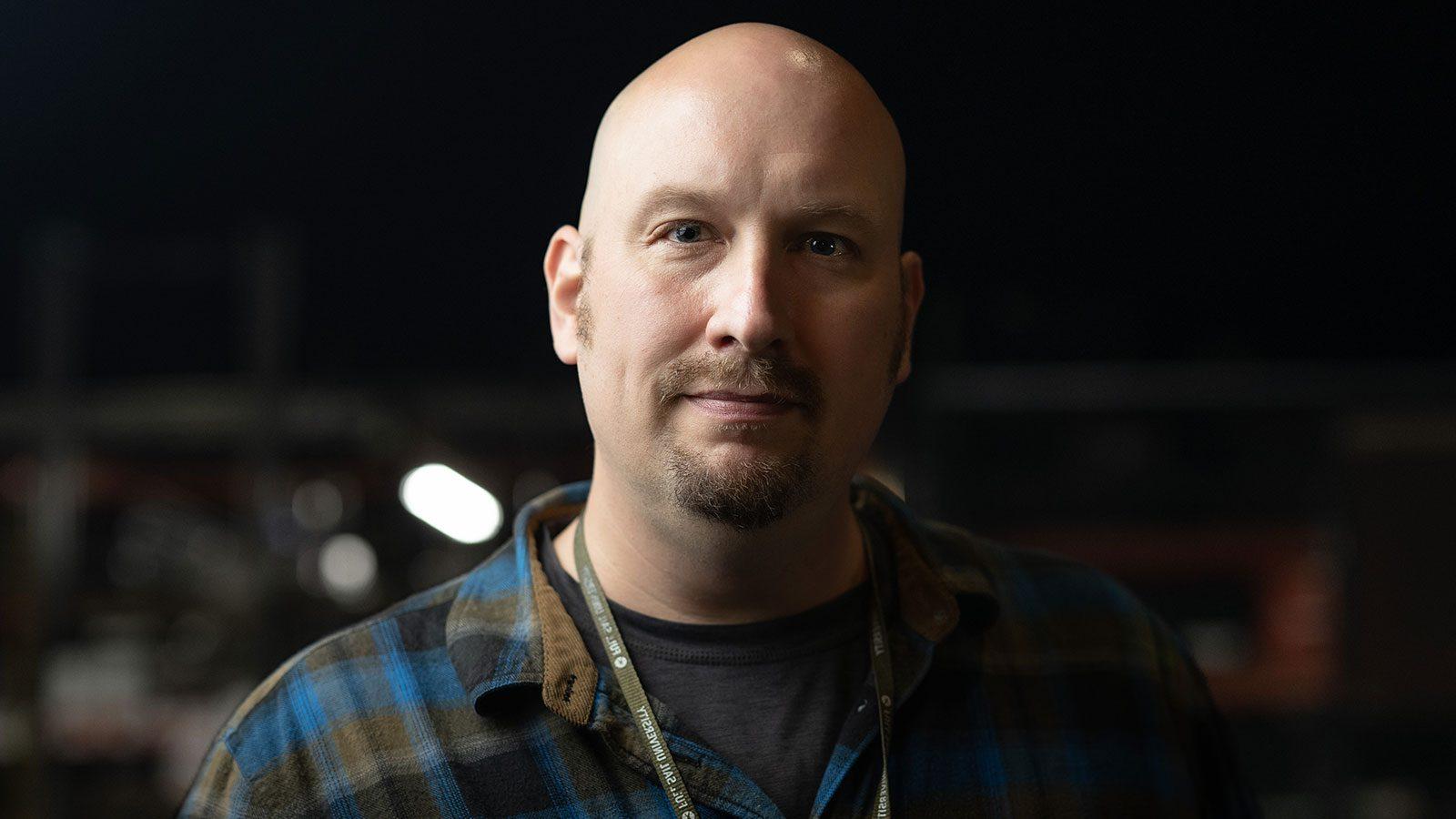 Headshot of Andrew Garraway wearing a blue and grey plaid flannel and a Full Sail lanyard, complete with Full Sail pins.