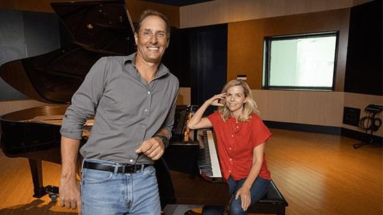 在Full Sail的音频神庙里，奥菲·奥多诺万坐在一架三角钢琴前. Darren Schneider leans against the piano.