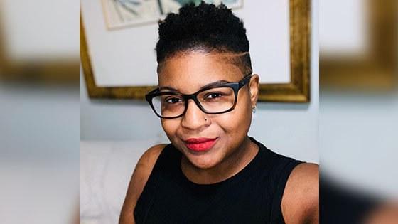 Instructor Ryan Phillips, a woman with black framed glasses and short black hair wearing a black blouse and red lipstick.