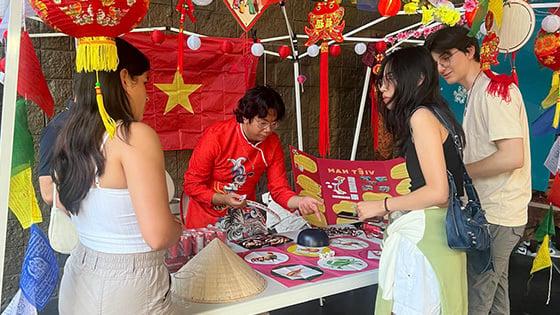 学生 gather around a table to play a game at APIC’s night-market event.