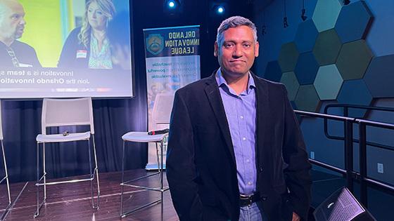 Rajiv Menon, founder of the Orlando Innovation League, poses in front of a stage at the Full Sail Treehouse.