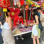 学生 gather around a table to play a game at APIC’s night-market event.