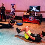 Two staff members take part in a bootcamp style workout instructed by a member of the Orange County Fire Rescue.