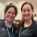 Michelle Moreno and Stacie Aldrich smiling and standing side by side wearing blue lanyards with conference badges and black Full Sail polo shirts.