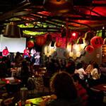 A group gathered at 满帆's Treehouse, guests sitting down and the hosts on stage. The room is dimly lit and decorated with red paper lanterns for the Lunar New Year.