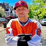 Full Sail Film Production MFA grad Panda Lord in an orange hockey jersey on a residential Philadelphia street.