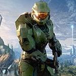 Halo main character Master Chief in signature green armor featuring the number 117 on his left chest plate in white, centered in front of a large grey triangular space ship with the words ‘Halo Infinite’ stylized in the bottom left corner.