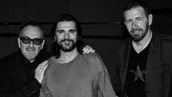 Sebastian stands next to Juanes and Elvis Costello. Sebastian wears a t-shirt and jacket, Juanes wears a t-shirt, Elvis wears a jacket.