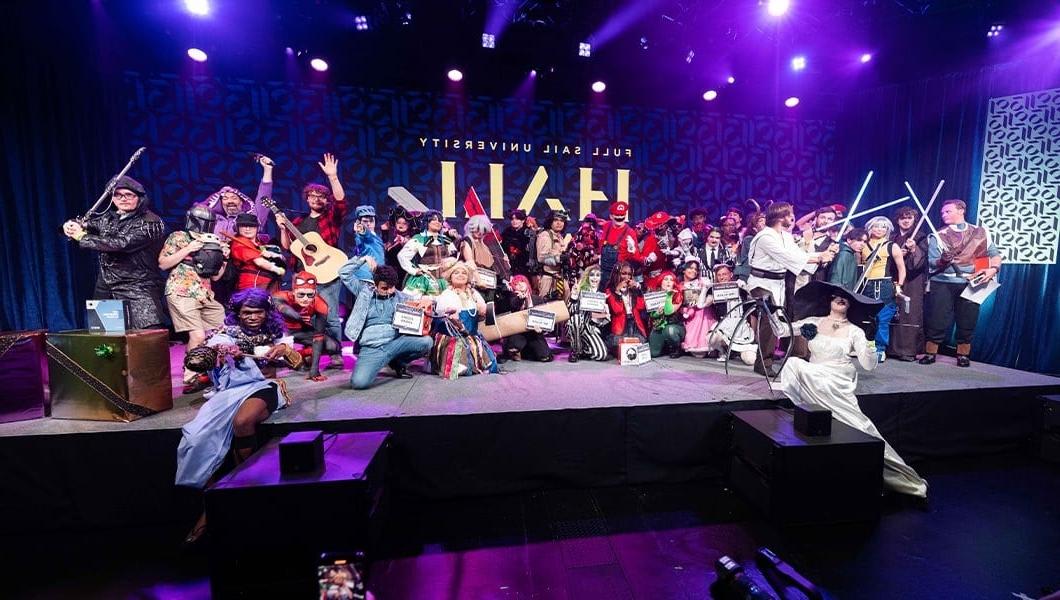 Several costume contest contestants pose enthusiastically on-stage. 他们都穿着色彩缤纷、创意十足的服装，借鉴了流行文化或动漫.