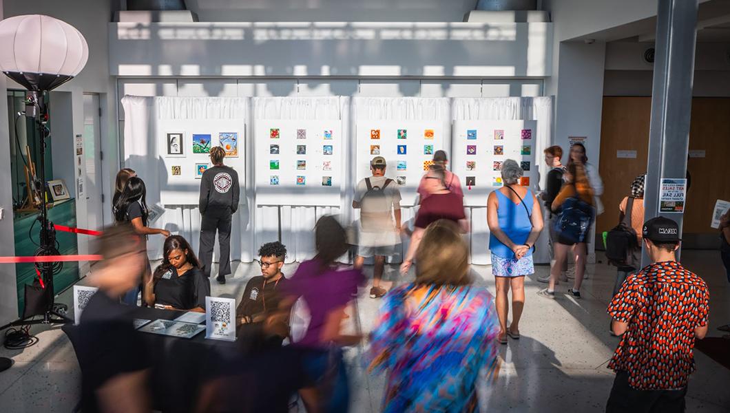 A long exposure image of people staring at the many small paintings hung up on the 满帆 Live lobby wall.